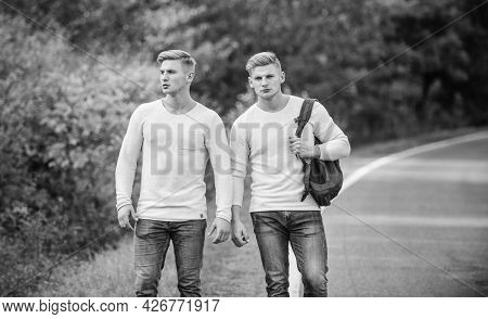 Means Of Travel. Twins Walking Along Road. Two Brothers Go Adventure. Friendship. Men Hitch Hiking. 
