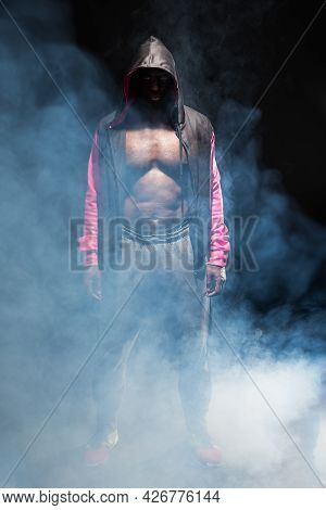 Muscular Adult Male In Hooded Jacket With Bare Torso With Smoke Around