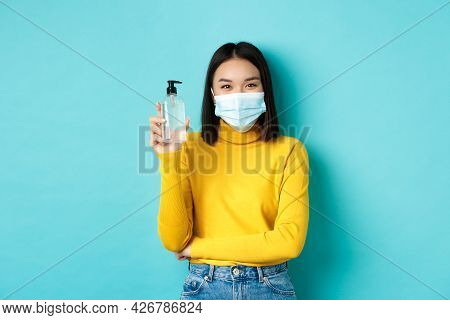 Covid-19, Social Distancing And Pandemic Concept. Cheerful Asian Woman Showing Hand Sanitizer, Recom
