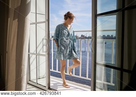 Woman In Deshabille Looks Out Into Street, Standing On Loggia In Her Apartment.
