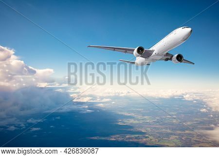 Commercial Airplane Flying Above Clouds On Blue Sky Background
