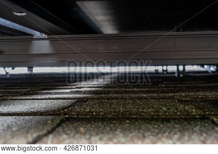 Gap Underneath Solar Panels And Asphalt Shingle Roof With Rails And Anchors Visible.