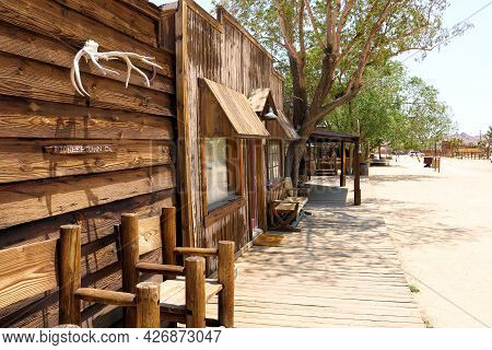 July 14, 2021 In Pioneertown, Ca:  Chairs Besides A Rustic Wooden Building With Hanging Antlers Take