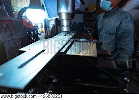 A Man Wear Surgical Mask Working With Milling Machine. Tool For Cut Metal Workpiece. Vertical Millin