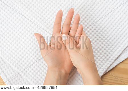 One Female Hand Massages The Other Hand Lying On A White Towel With The Open Palm Up. Closeup Hand O