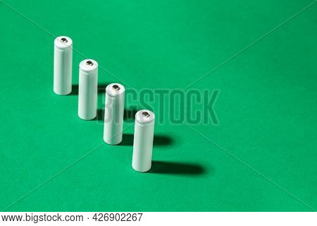 White Aa Batteries On A Green Background. Space For Text. Recycling Of Rechargeable Nimh Batteries.