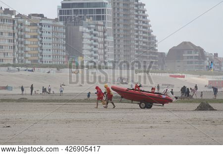 Nieuwpoort, Belgium, 15 July 2021: Lifeguards On The Beach, Moving A Rescue Boat, On A Busy Summers 