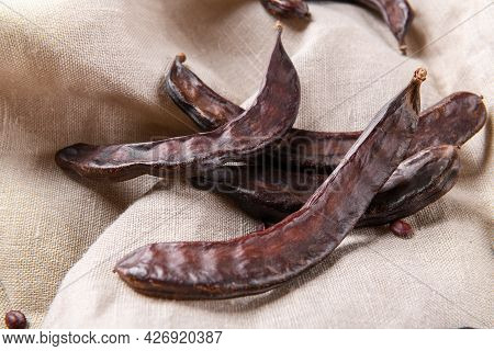 Dry Raw Carob Pods On Wooden Background