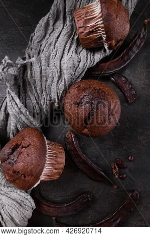 Chocolate Carob Cupcakes Cooking With Carob Powder And Dried Carob Pods On A Dark Background. Organi