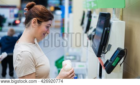 Caucasian Woman Uses A Self-checkout Counter. Self-purchase Of Groceries In The Supermarket Without 