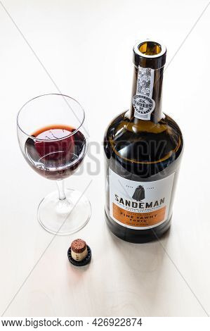 Moscow, Russia - June 10, 2021: Wine Glass, Cork And Open Bottle Of Sandeman Fine Tawny Porto Wine. 