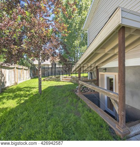 Square Frame Separate Basement Apartment Entrance With Stairs, Glass Panel And Trees On The Lawn At 