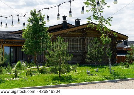 Beautiful Wooden House With Garlands On The Background Of Landscape Design