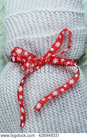 Christmas Backgound, Warm Wool Knitted Scarf  With The Red Ribbon. Concept Of Christmas Gifts With L