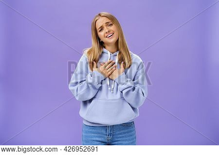 Sighing Touched And Pleased Beautiful Young Girl With Blond Hair In Hoodie Holding Palms On Heart An