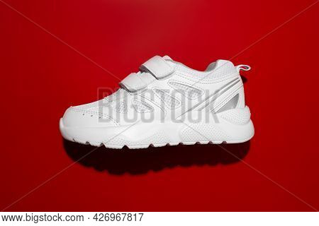 Flat Lay Macro White Kid Sneaker With Velcro Fasteners Located On The Side With Hard Summer Shadows 