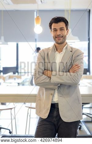 Handsome Young Businessman With Folded Arms In The Office. Cheerful Self Confident Man With Crossed 