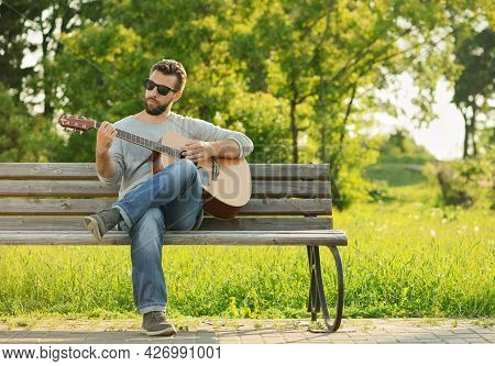 Caucasian Man, 30 Years Old, Is Playing His Classical Guitar In Park At Sunset.