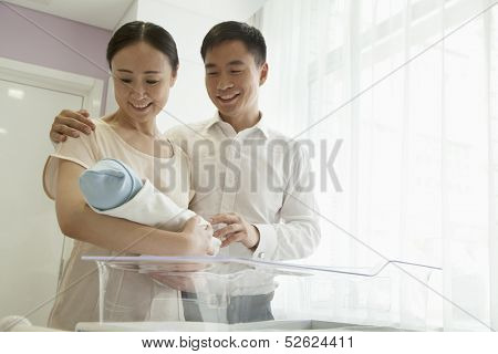 Young happy family holding their newborn in the hospital 