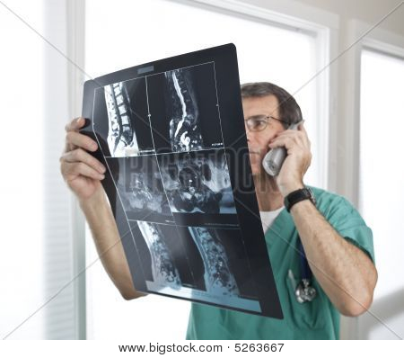 Doctor Reviewing Patient Radiology Scans And Discussing On The Telephone