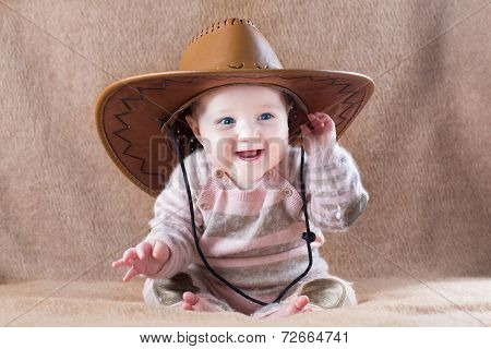 Happy laughing baby wearing a cow girl outfit with a big hat
