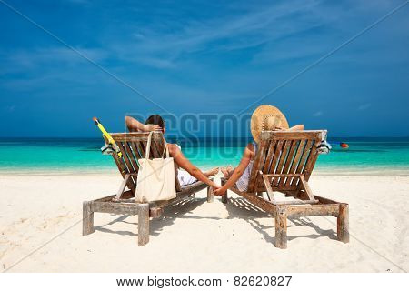 Couple in white relax on a tropical beach at Maldives