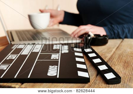 Female hands of scriptwriter working on laptop at desk on cupboard background