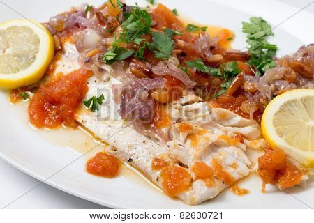Baked fish with tomato sauce and an  onion and pine nut garnish, a delicious traditional Near Eastern dish from Lebanon/Syria/Jordan,tajine samak bi banadura