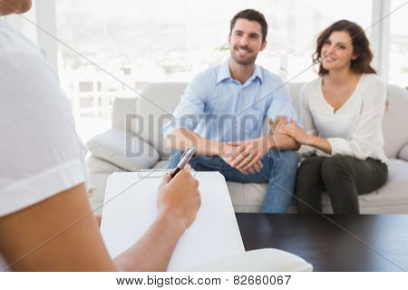 Reconciled couple smiling and talking with their therapist in the office