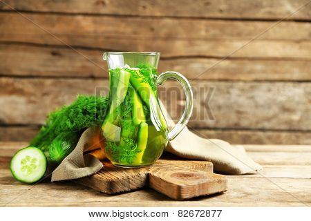 Glass ewer with fresh organic cucumber water on wooden table