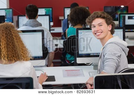 Student smiling at camera in computer class at the college