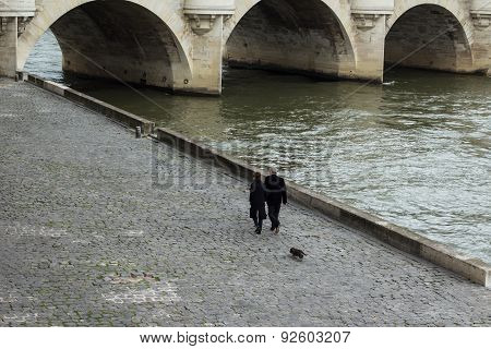 Couple walk their dog along river Seine, Paris