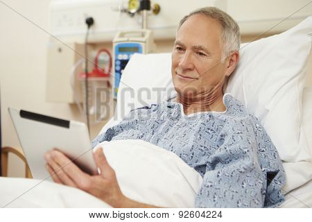 Senior Male Patient Using Digital Tablet In Hospital Bed