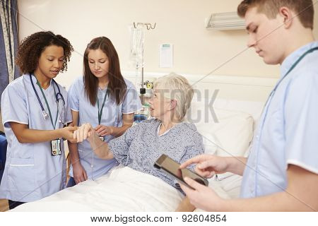 Trainee Nursing Staff By Female Patient's Bed In Hospital