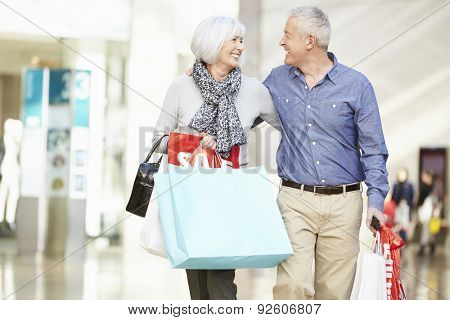 Happy Senior Couple Carrying Bags In Shopping Mall