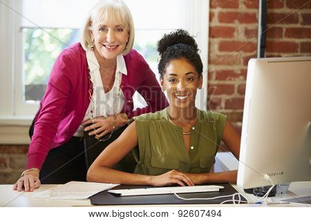 Two Women Working At Computer In Contemporary Office