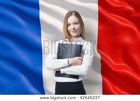 Smiling Business Lady In A White Shirt With A Black Folder. French Flag As A Background.