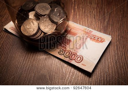 Bundle Of Bank Notes And A Glass Jar With Coins
