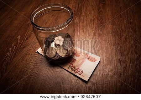 Bundle Of Bank Notes And A Glass Jar With Coins