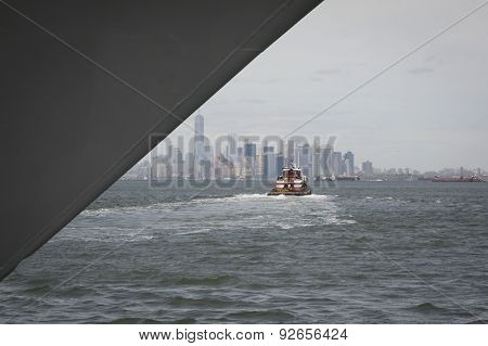 STATEN ISLAND, NY - MAY 20 2015: Harbor tug Ellen McAllister heads toward Lower Manhattan after helping a Navy ship dock at Sullivans Pier in Staten Island at the beginning of Fleet Week in New York. 