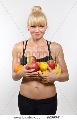 Attractive happy middle-age fit woman holding fruit and vegetables. Healthy eating, fitness, diet, vegetarianism and rawfoodist concept.