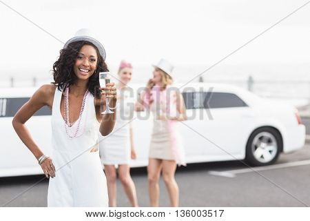 Frivolous women drinking champagne next to a limousine on a night out