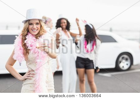 Frivolous women drinking champagne next to a limousine on a night out