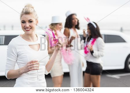 Frivolous women drinking champagne next to a limousine on a night out