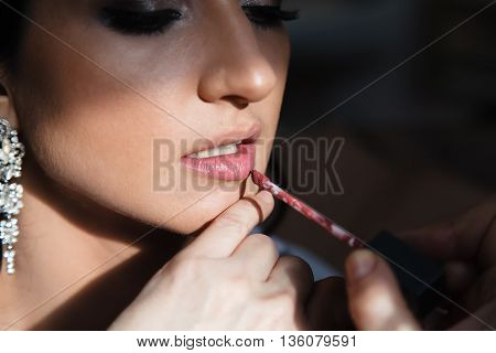 Wedding makeup artist making a make up for bride. Beautiful sexy model girl indoors. Bridal morning of a cute lady