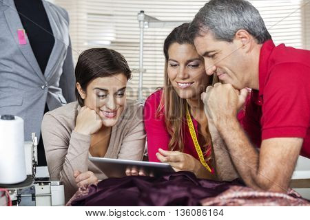 Smiling Tailors Using Digital Tablet In Factory