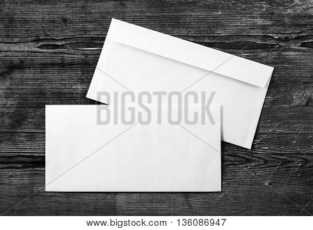 Photo of two blank envelopes on a dark wooden background. Back and front. Template for design portfolios. Mock-up for your design. Top view.