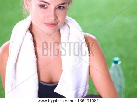 Beautiful young woman relaxing after exerscises on the grass.