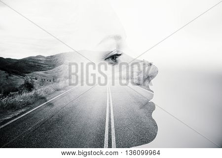 Side view of thoughtful woman's face on road and landscape background. Black and white image. Double exposure