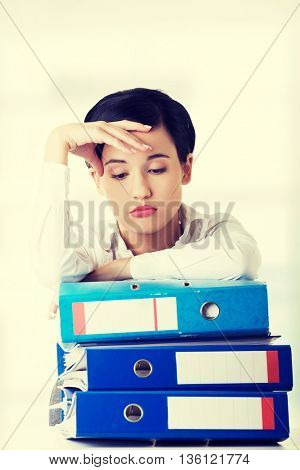 Sad woman with ringbinders sitting at the desk.